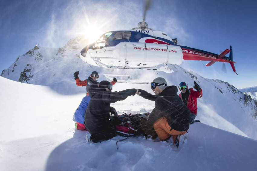 mabey ski heli-skiing adventure to new zealand, helicopter flying above skiers