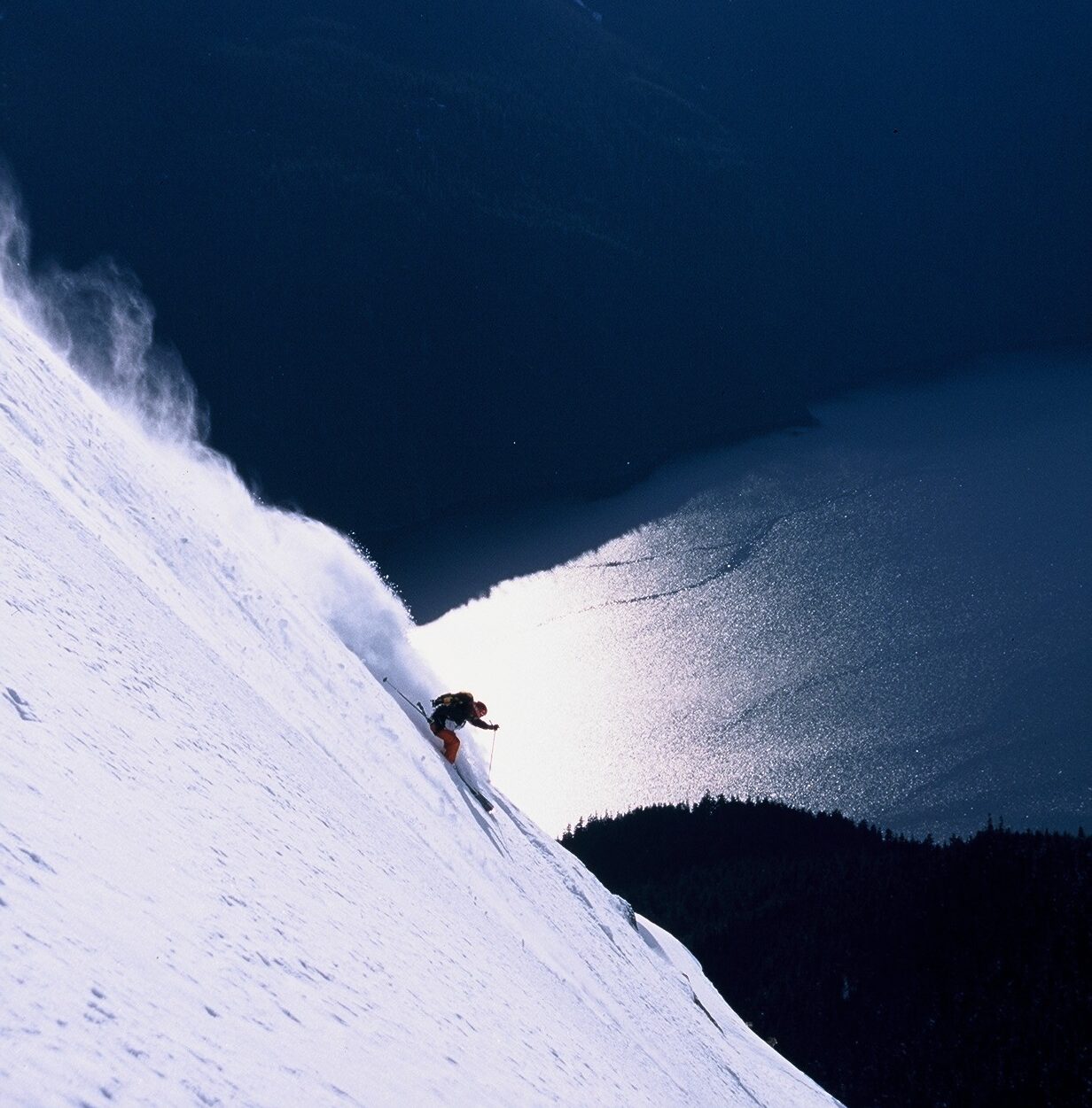 Bella Coola skiing down steep mountain face heli-skiing