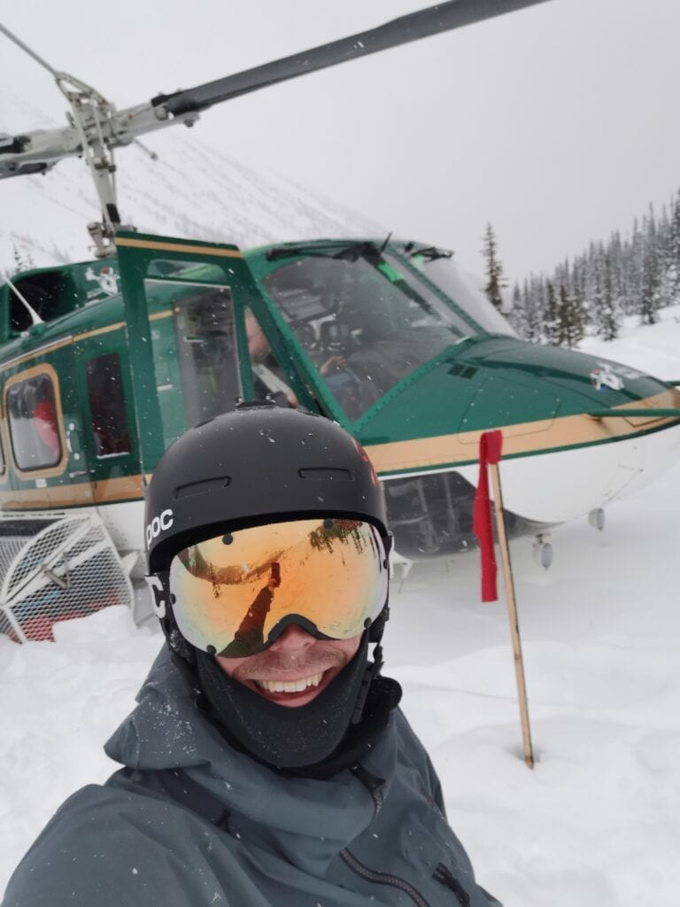 skier standing in front of helicopter with snow on the ground
