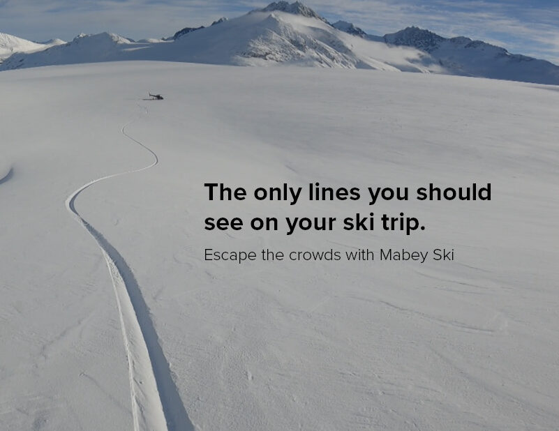 single ski line in fresh snow leading to helicopter with advertising caption