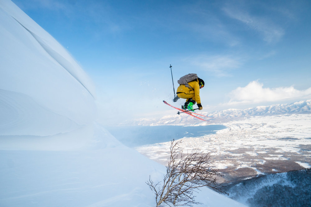 skier jumping into the sky with snow flying around